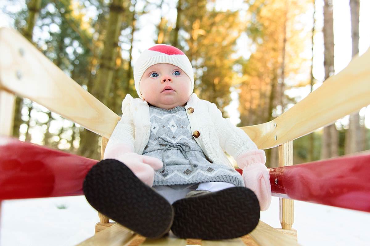 6 month old baby girl on a sled in wisconsin winter