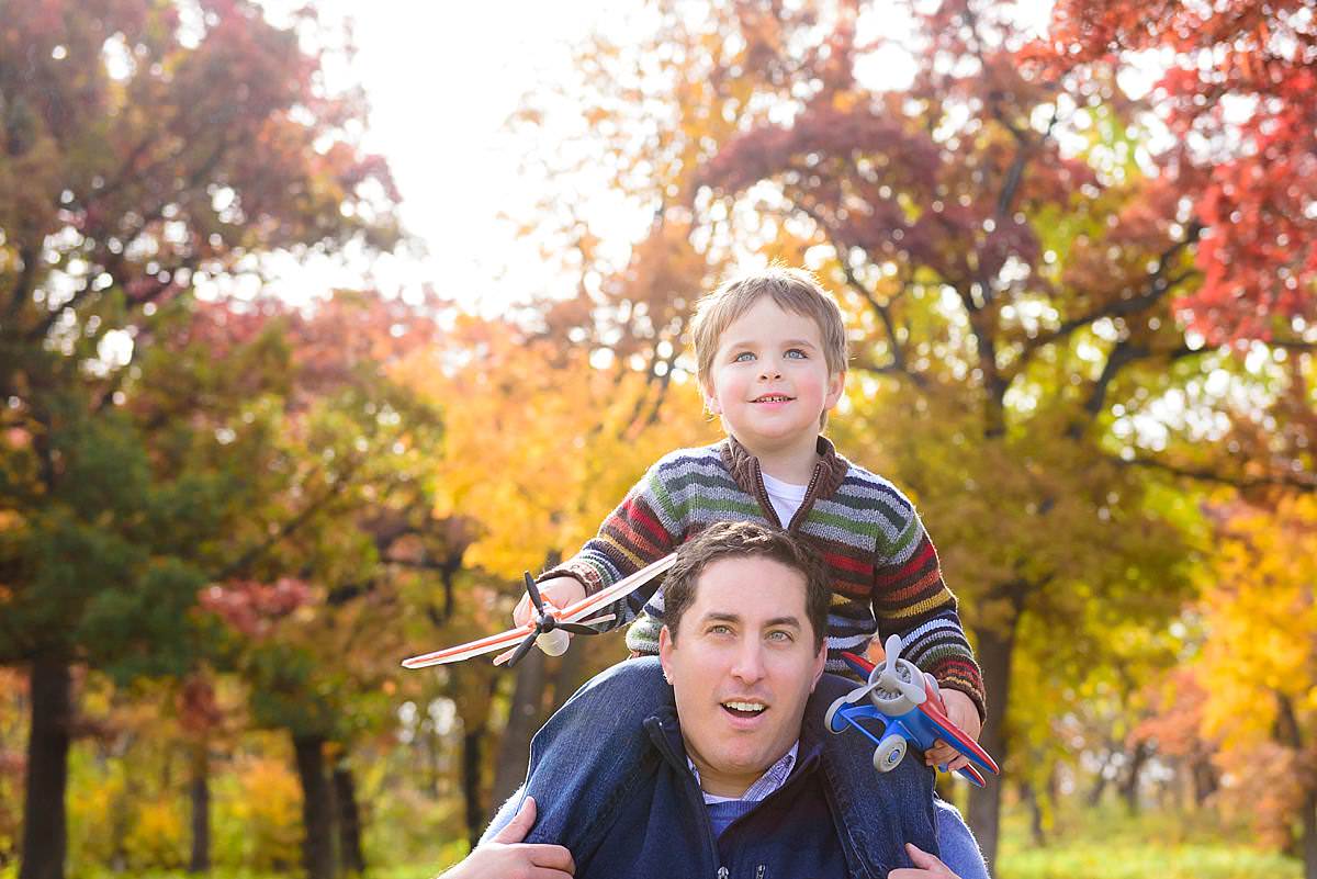 father and son playing airplane at olin park in the autumn