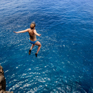 woman jumping off a cliff into the Pacific Ocean