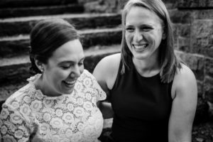 Two brides sit and laugh together at their wedding