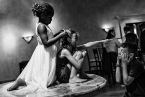 kids on a table at a wedding with a girl bossing an exhausted boy around
