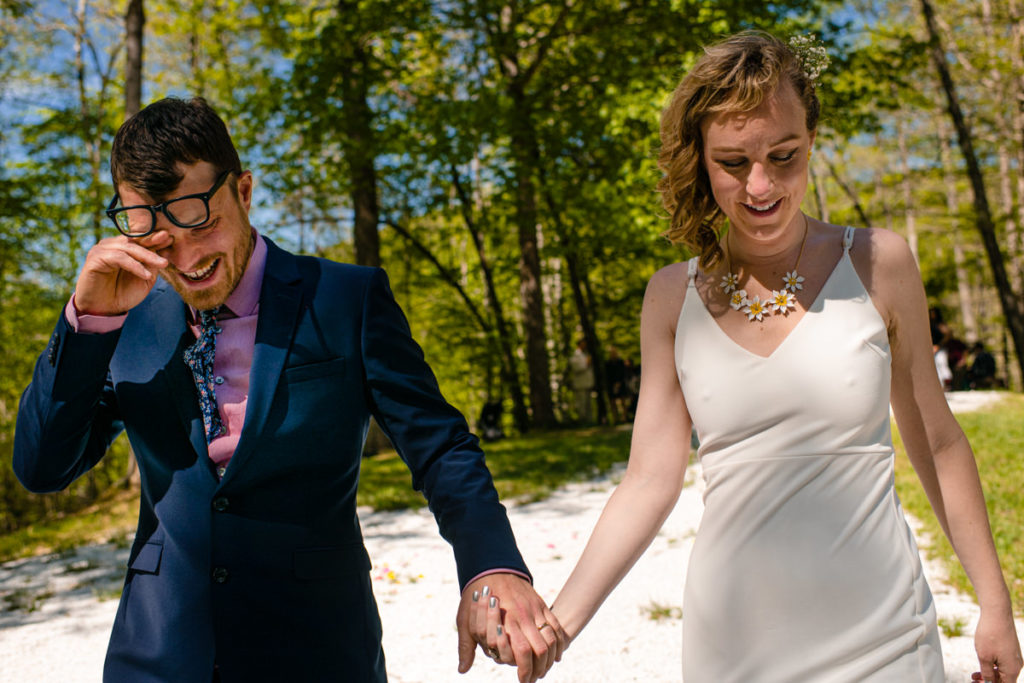 bride consoles her new groom by holding his hand at the end of a wedding ceremony