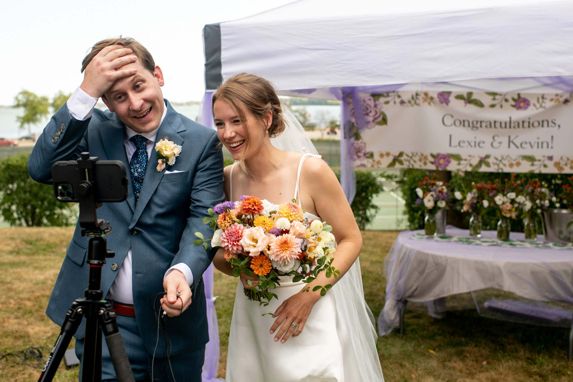 A bride and groom chat via zoom with their family on a cell phone