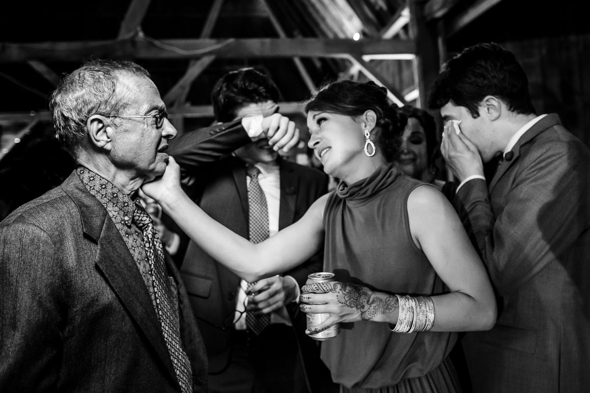 Daughter comforts father after father-daughter dance at wedding while her brothers cry in the background