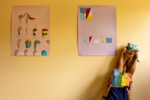 mom and daughter are upside down against a yellow wall with a poster and stuffed kitty