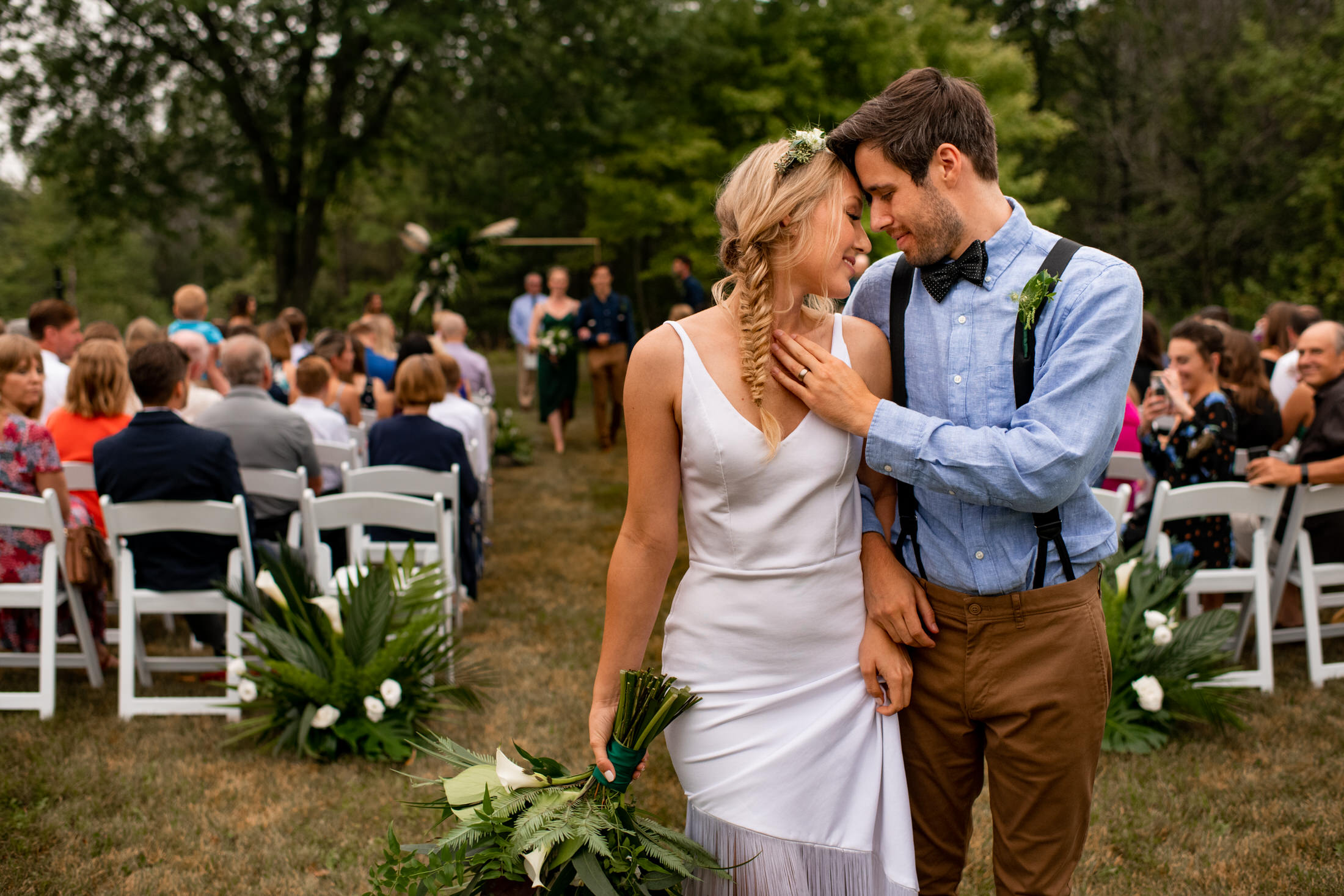 Groom touches brides chest while recessing from ceremony at a backyard wedding