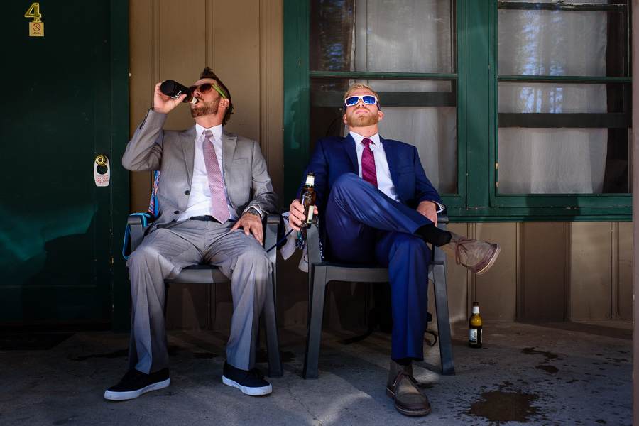 Groom and groomsman drink beer outside of hotel in Lake Tahoe with spilled beer on the ground