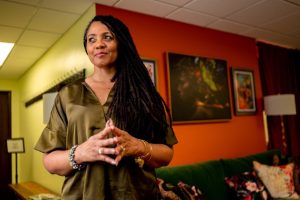 Woman stands with fingertips touching as she poses for a portrait.