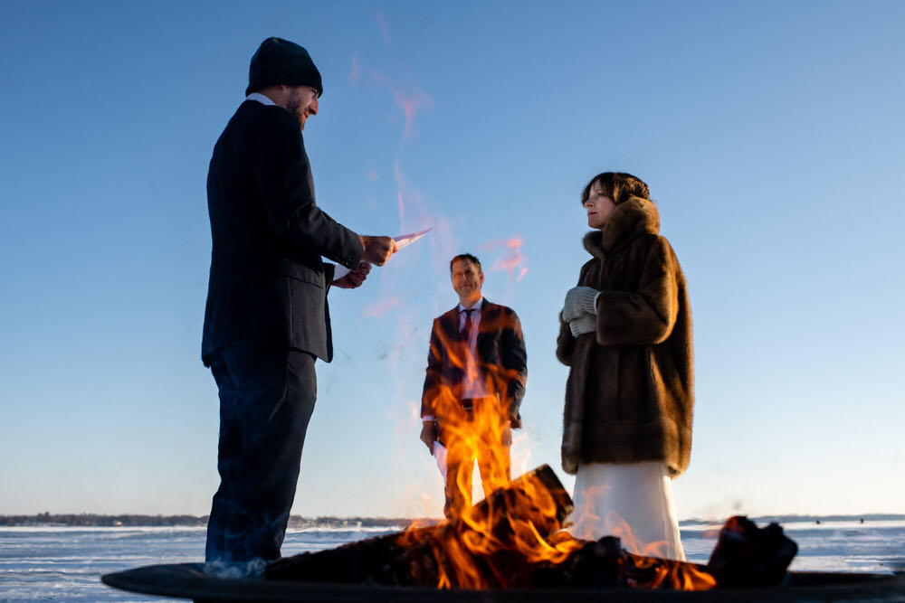 A couple gets married on frozen lake Monona in Madison Wisconsin in front of a portable fire pit.