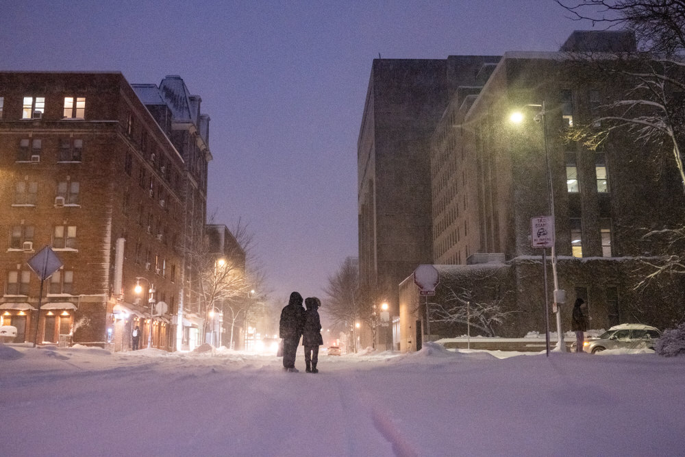 People pause at the intersection of Lake Street and Langdon Street during the winter storm in Madison on Friday, Jan. 12, 2024.