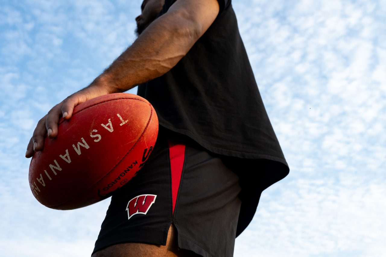 A Wisconsin Wombats player holds an Australian rules football in his hand during team practice at Olbrich Park in Madison.